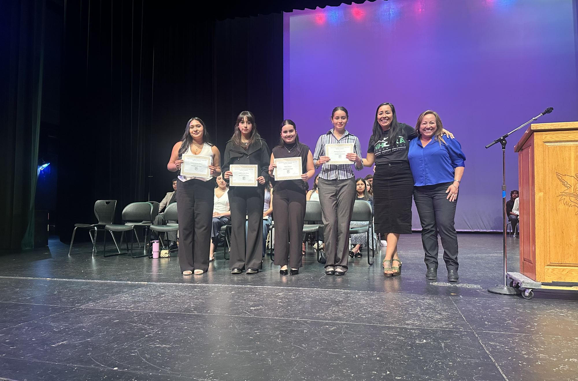 NHORA Santa Cruz scholarship recipients holding their certificates on stage with chapter leaders