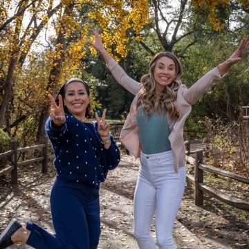 Leslie Cruz-Kelly y Jessica Naegele saltando de alegría en un sendero con hojas de otoño